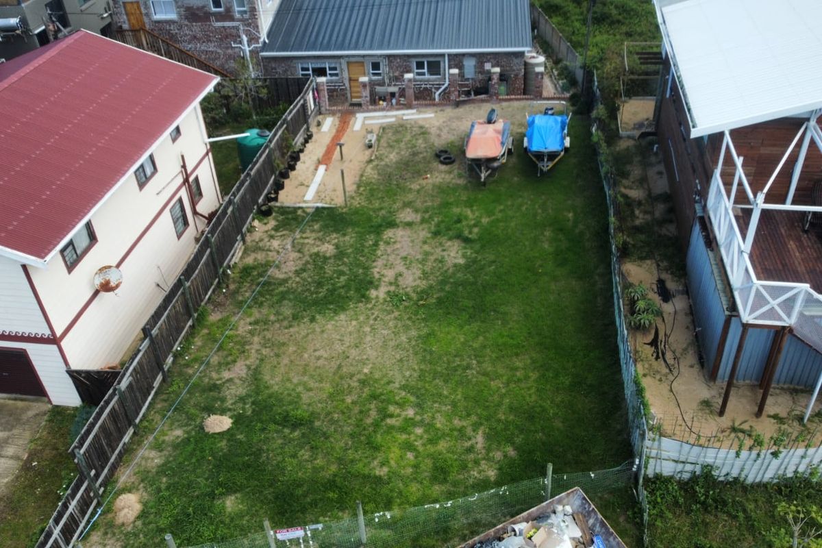 Aerial view of a residential vacant land plot featuring a grass lawn, perimeter fencing, and a water tank.