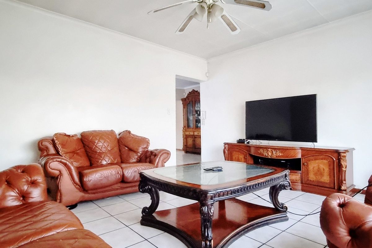 A spacious living room featuring ceramic floor tiles and a ceiling fan, providing a comfortable area for relaxation.