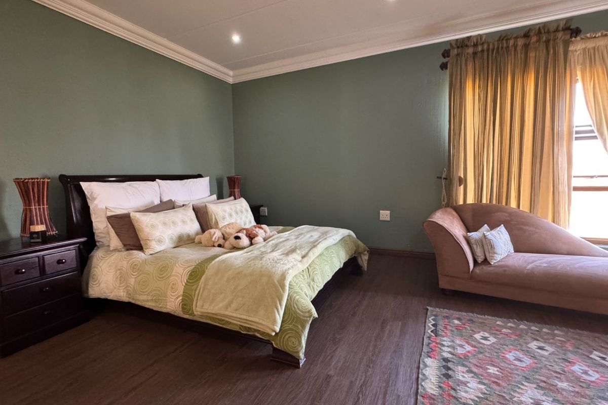A spacious bedroom featuring dark laminate flooring, crown molding, and recessed lighting, providing a comfortable and well-maintained living space.
