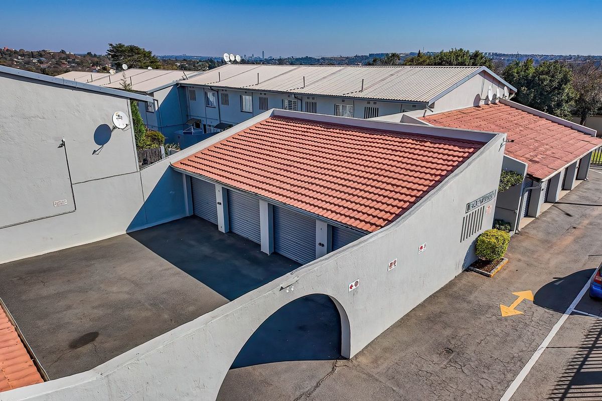 Aerial view of the townhouse complex featuring multiple garage units with tiled roofing and an asphalt driveway.