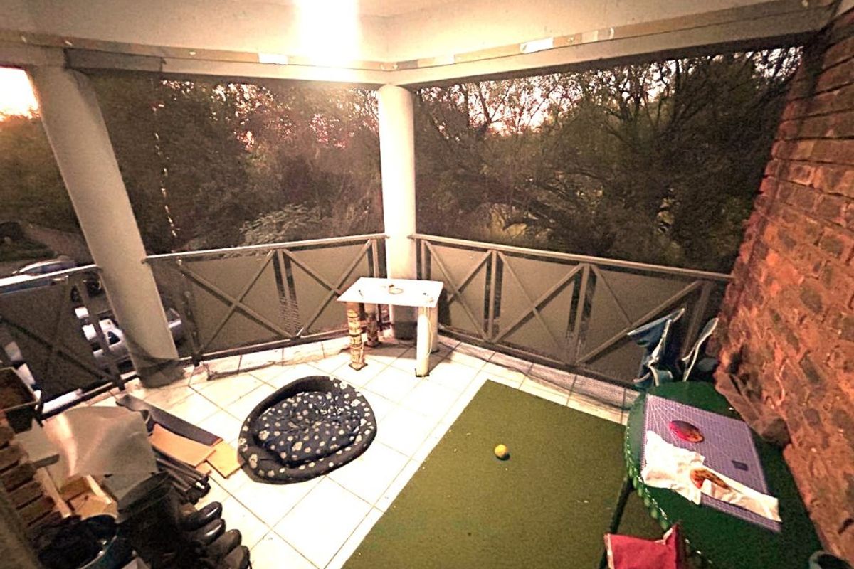 Covered balcony featuring tiled flooring, a metal balustrade, and an exposed brick wall, offering an outdoor space with potential for improvement.