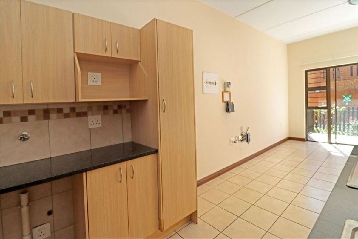 An empty kitchen featuring laminate cabinetry, granite countertops, and tiled flooring, with direct access to an outdoor area via a sliding glass door.