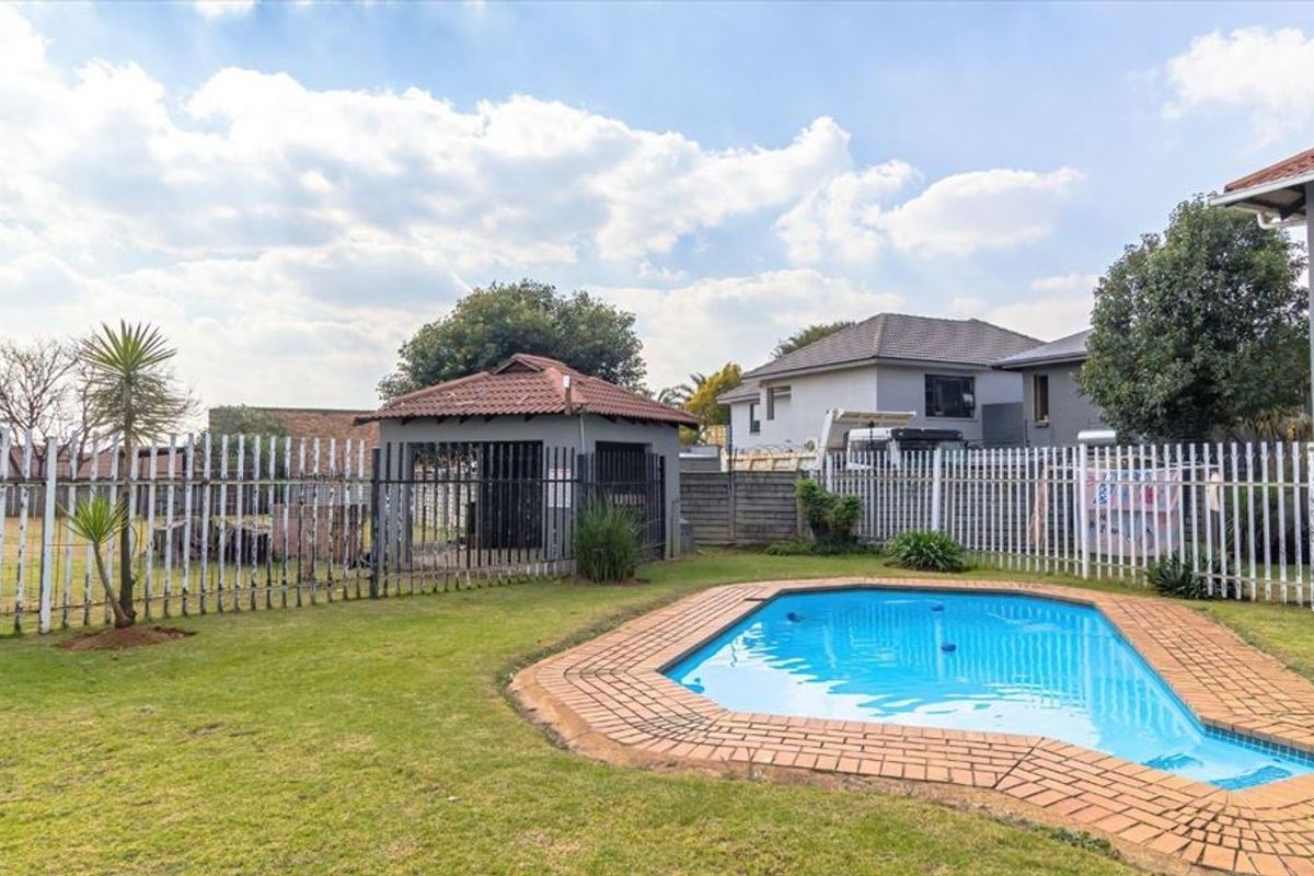 Rear garden area featuring a swimming pool with brick coping, a detached gazebo, and metal perimeter fencing.