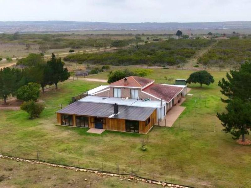 Aerial view of a farm property featuring a multi-section dwelling with a combination of tiled and metal roofing, set within a large rural landscape.
