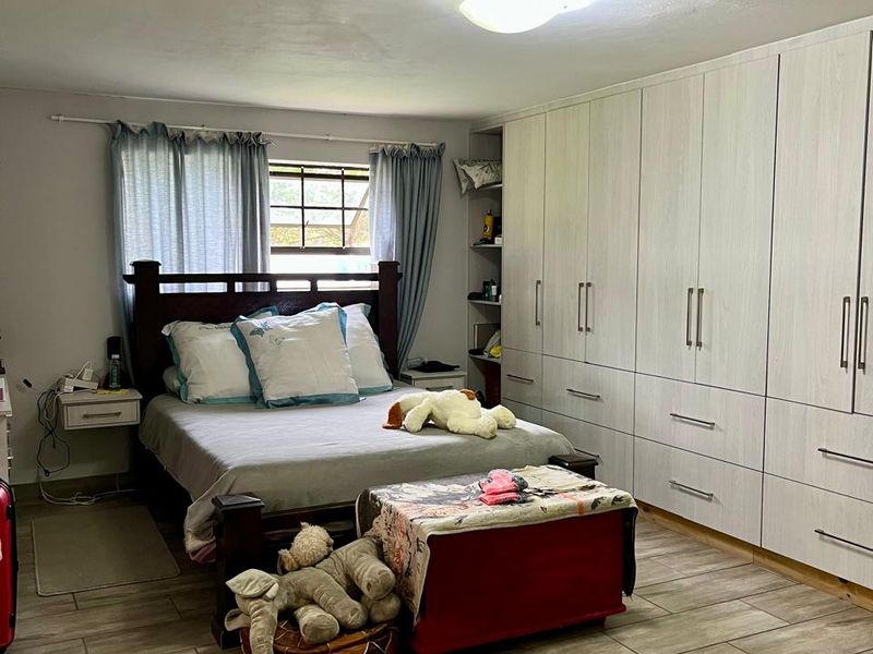A well-maintained bedroom featuring extensive built-in cabinetry, modern wood-look tiled flooring, and a functional layout with natural light.