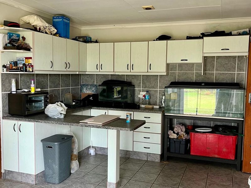 A dated kitchen area featuring laminate cabinetry, tiled backsplash, and ceramic floor tiles, offering a functional layout with potential for modernization.