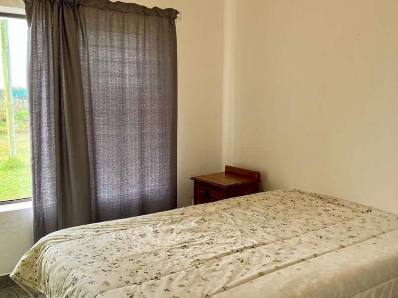 A simple bedroom featuring tiled flooring and neutral wall finishes, providing a functional space with natural light.