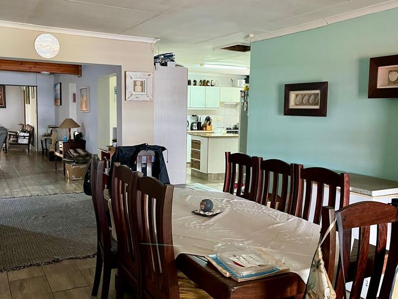 Open plan dining area featuring tiled flooring and ceiling track lighting, with a view through to the adjacent kitchen space.