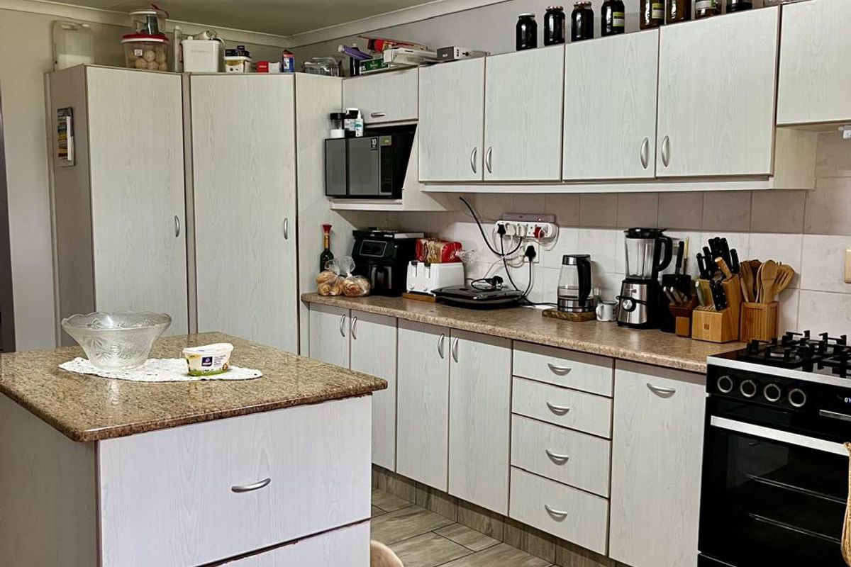Functional kitchen featuring a central island, granite countertops, ample built-in cabinetry, and a gas stove, finished with durable tiled flooring.