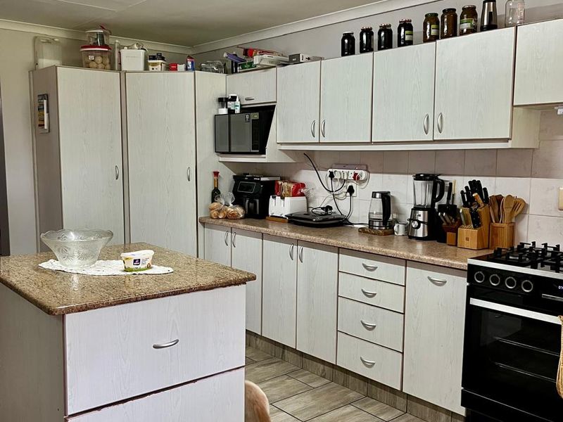 Functional kitchen featuring a central island, granite countertops, ample built-in cabinetry, and a gas stove, finished with durable tiled flooring.
