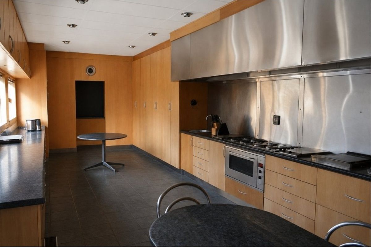 Spacious kitchen featuring extensive light wood cabinetry, stainless steel appliances, stone countertops, and a functional layout with integrated cooking and prep areas.