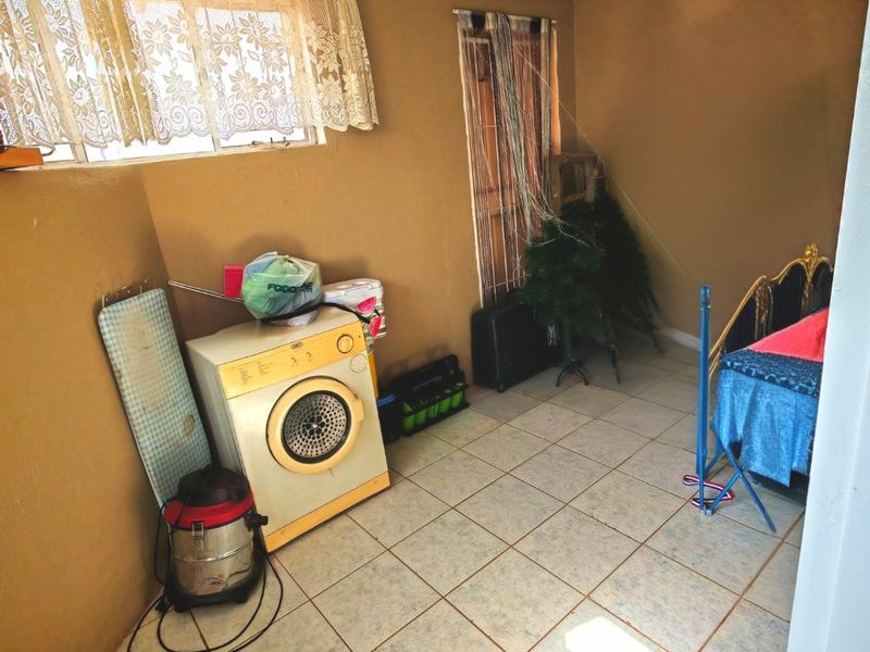 A functional laundry area featuring tiled flooring and natural light, suitable for utility use or potential renovation.