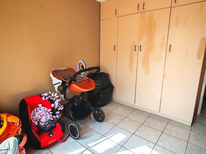 Bedroom featuring built-in cupboards and tiled flooring, currently used for storage.
