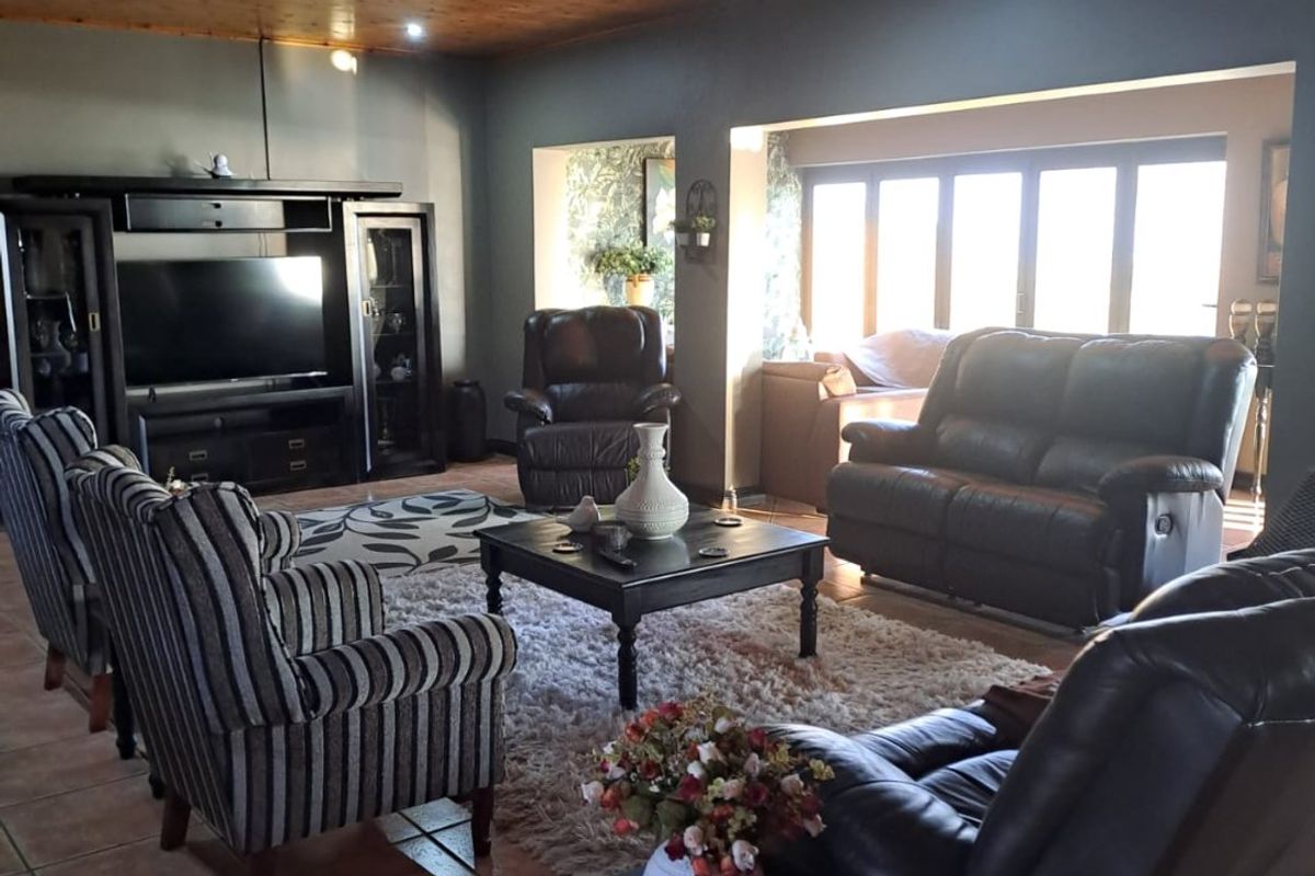 Spacious living room featuring a warm timber-clad ceiling, tiled flooring, and large windows that provide ample natural light.