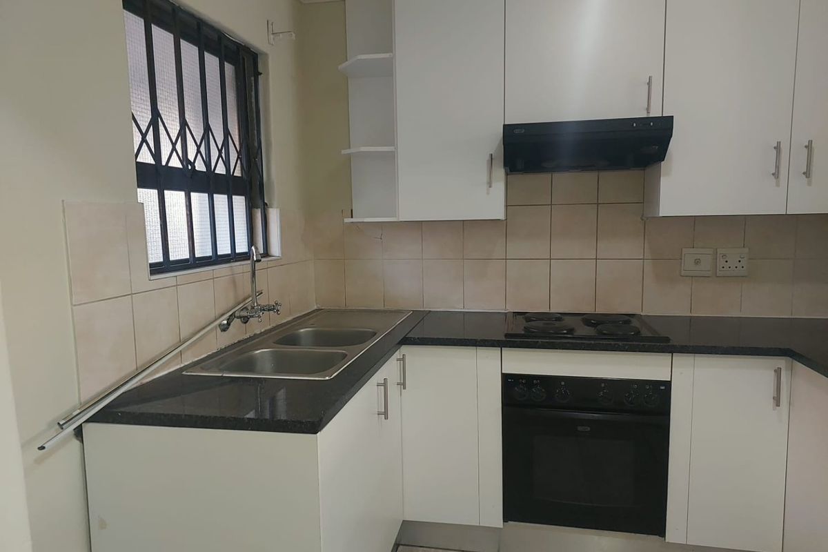 A functional kitchen featuring white cabinetry, granite countertops, a double sink, and built-in oven with an extractor fan.