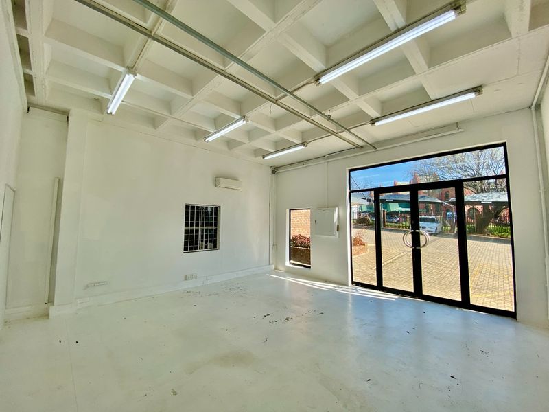 Open-plan industrial utility space featuring a waffle slab ceiling, fluorescent lighting, split system air conditioning, and large glass entrance doors.