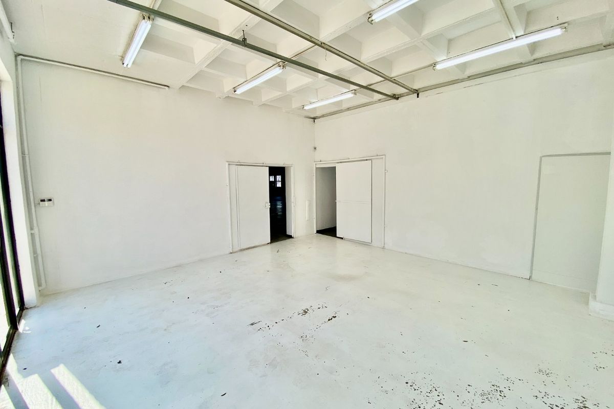 Spacious industrial utility area featuring an exposed waffle slab ceiling, fluorescent lighting, and durable painted concrete flooring, suitable for various commercial or storage uses.