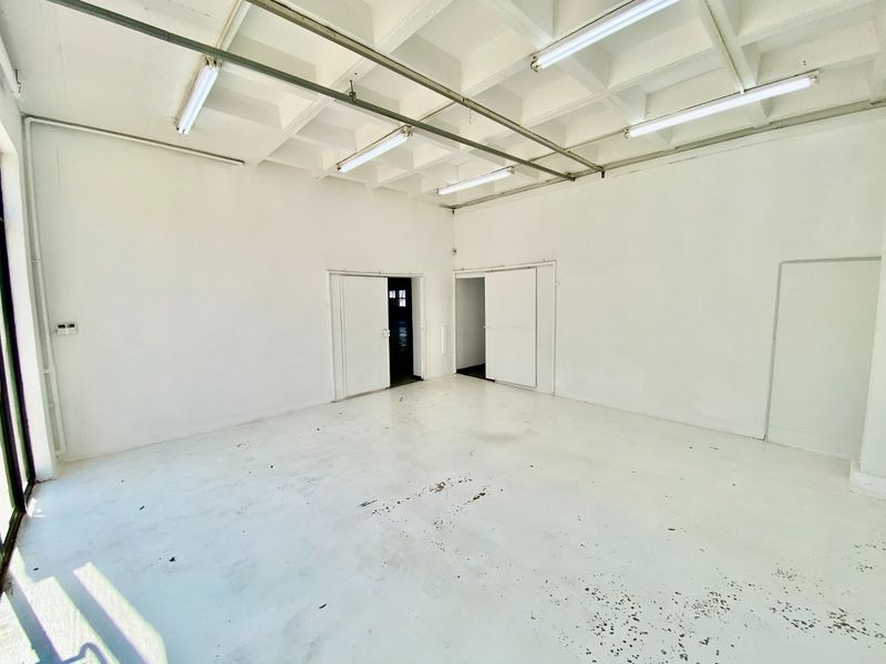 Spacious industrial utility area featuring an exposed waffle slab ceiling, fluorescent lighting, and durable painted concrete flooring, suitable for various commercial or storage uses.