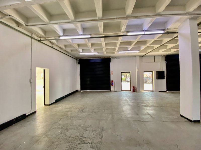 Spacious industrial warehouse unit featuring a high waffle slab ceiling, concrete flooring, and multiple roller shutter doors for efficient access.