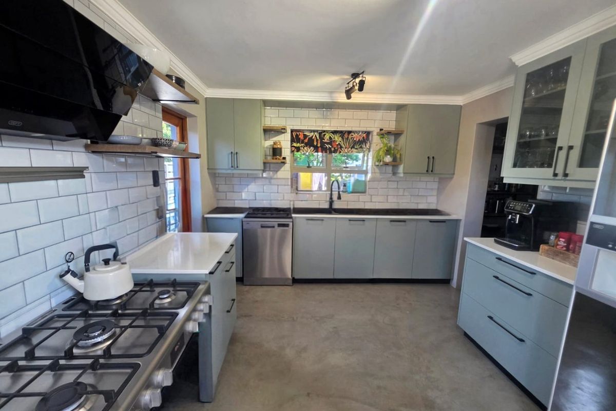 Modern kitchen featuring sage green cabinetry, subway tile backsplash, gas stove with extractor fan, stainless steel dishwasher, and polished concrete flooring.