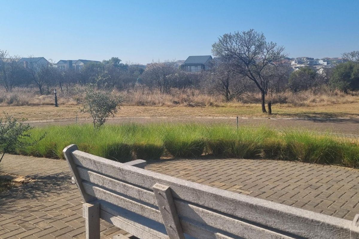 A view of the surrounding residential landscape and open space from a paved walkway area.