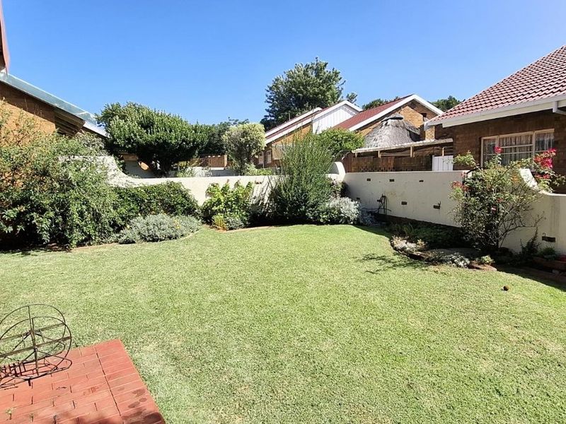 A private rear garden featuring a well-maintained lawn, brick boundary walls, and direct access to the home via a sliding door.