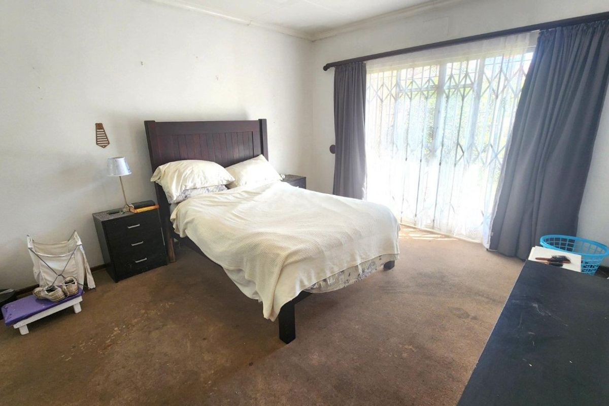 A bedroom featuring carpeted flooring and a sliding glass door with a security gate, providing access to the exterior.