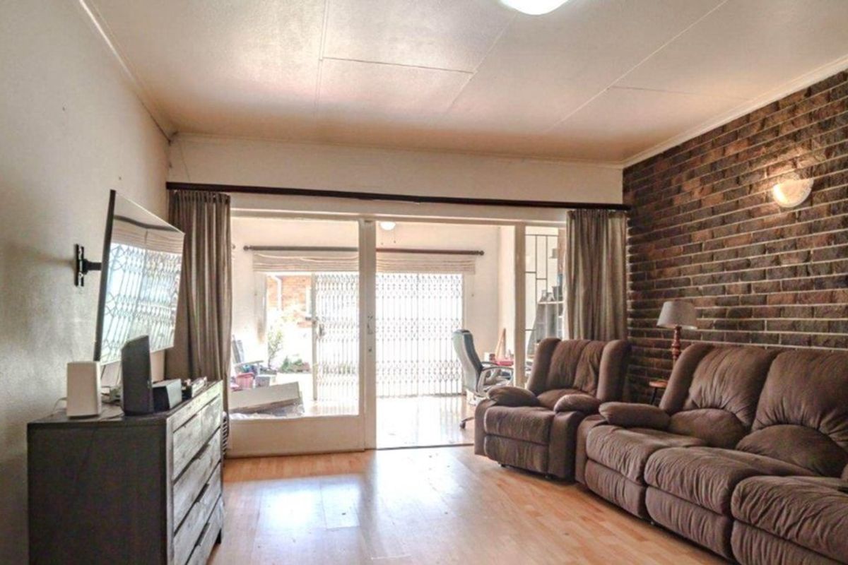 Spacious living room featuring an exposed brick wall, laminate flooring, and large sliding glass doors providing access to the outdoor area.