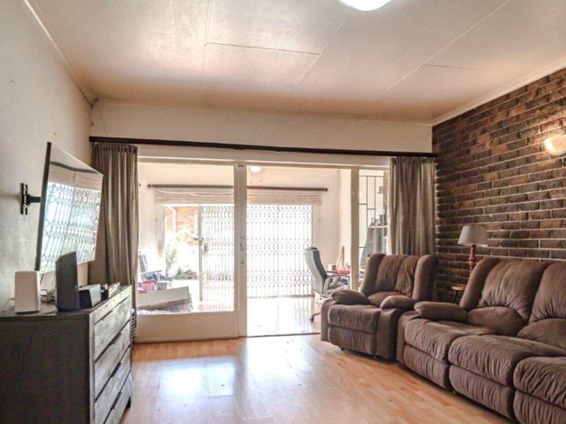 Spacious living room featuring an exposed brick wall, laminate flooring, and large sliding glass doors providing access to the outdoor area.