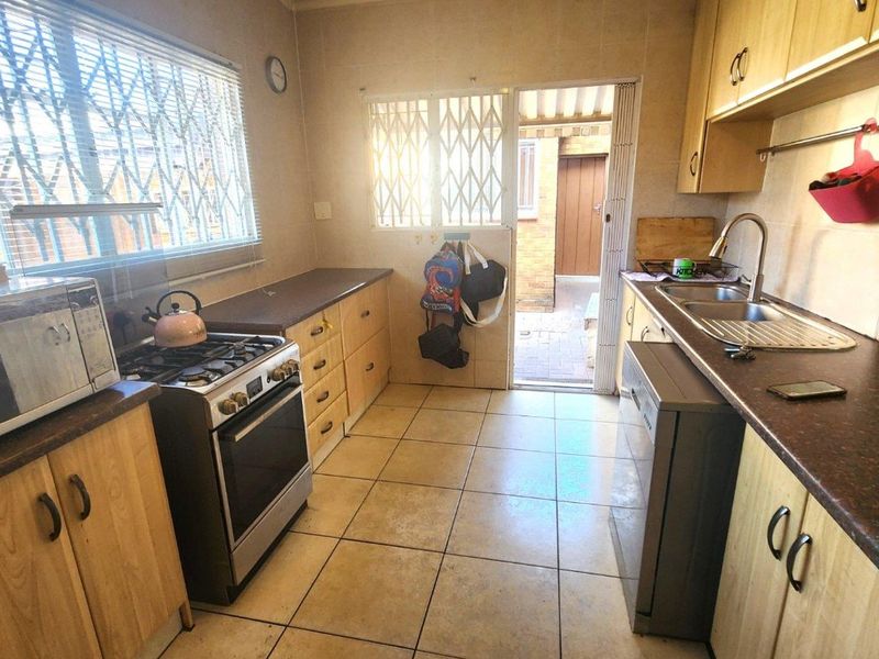 Functional kitchen featuring laminate cabinetry, gas stove, stainless steel sink, and direct access to an outdoor area through a security gate.