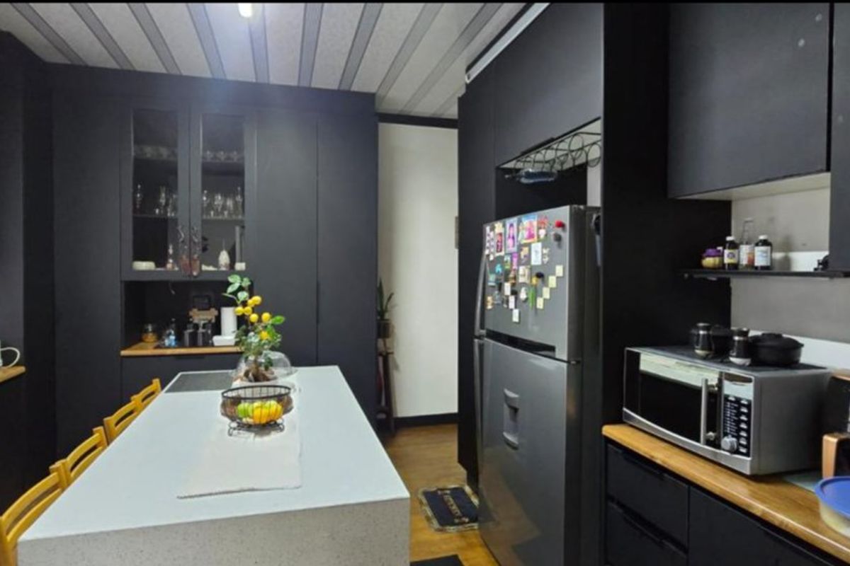 Modern kitchen featuring matte black cabinetry, a central stone-topped island, and integrated storage solutions, creating a sleek and functional culinary space.