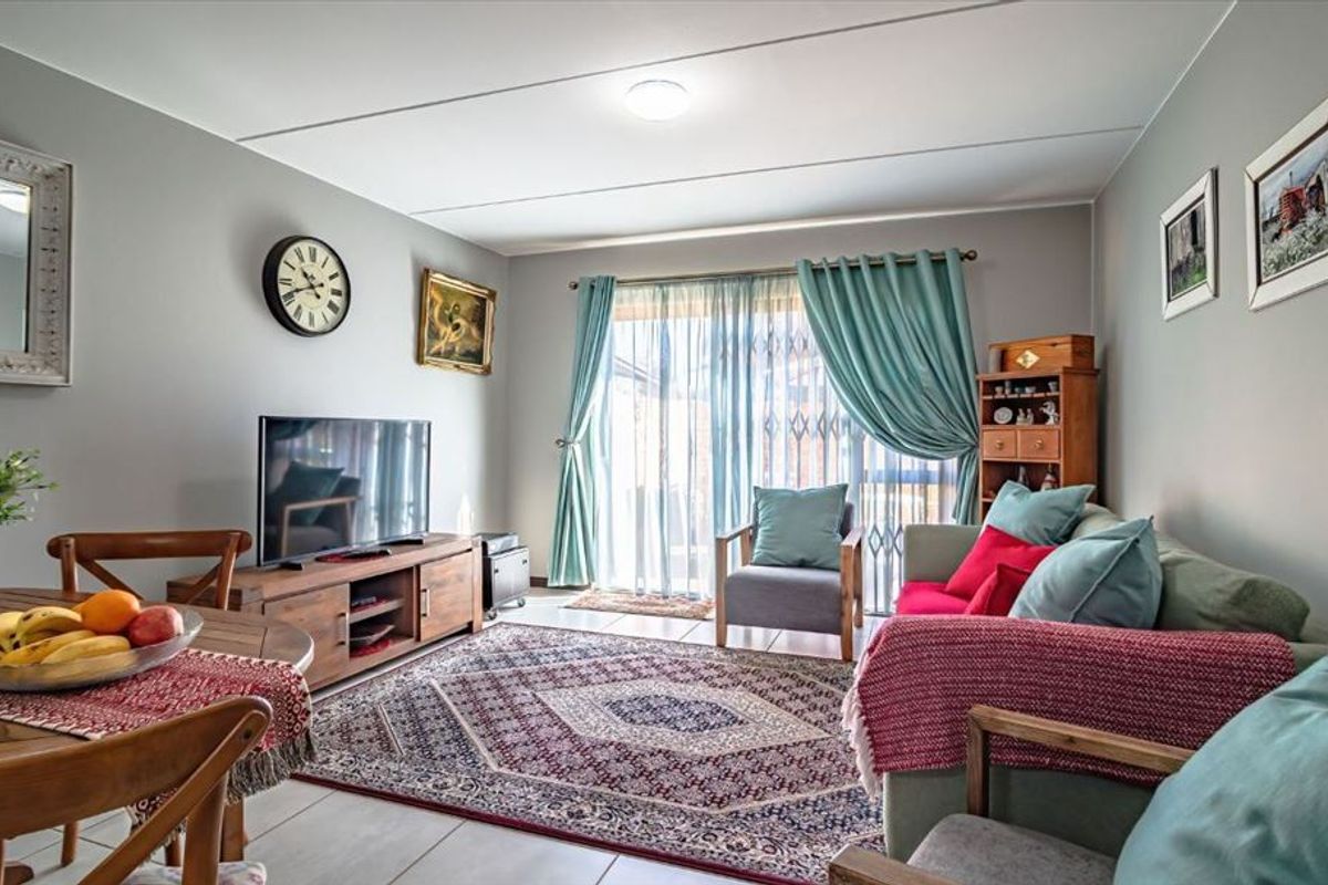 A comfortable living room featuring tiled flooring and a sliding glass door that provides access to the outdoor area.
