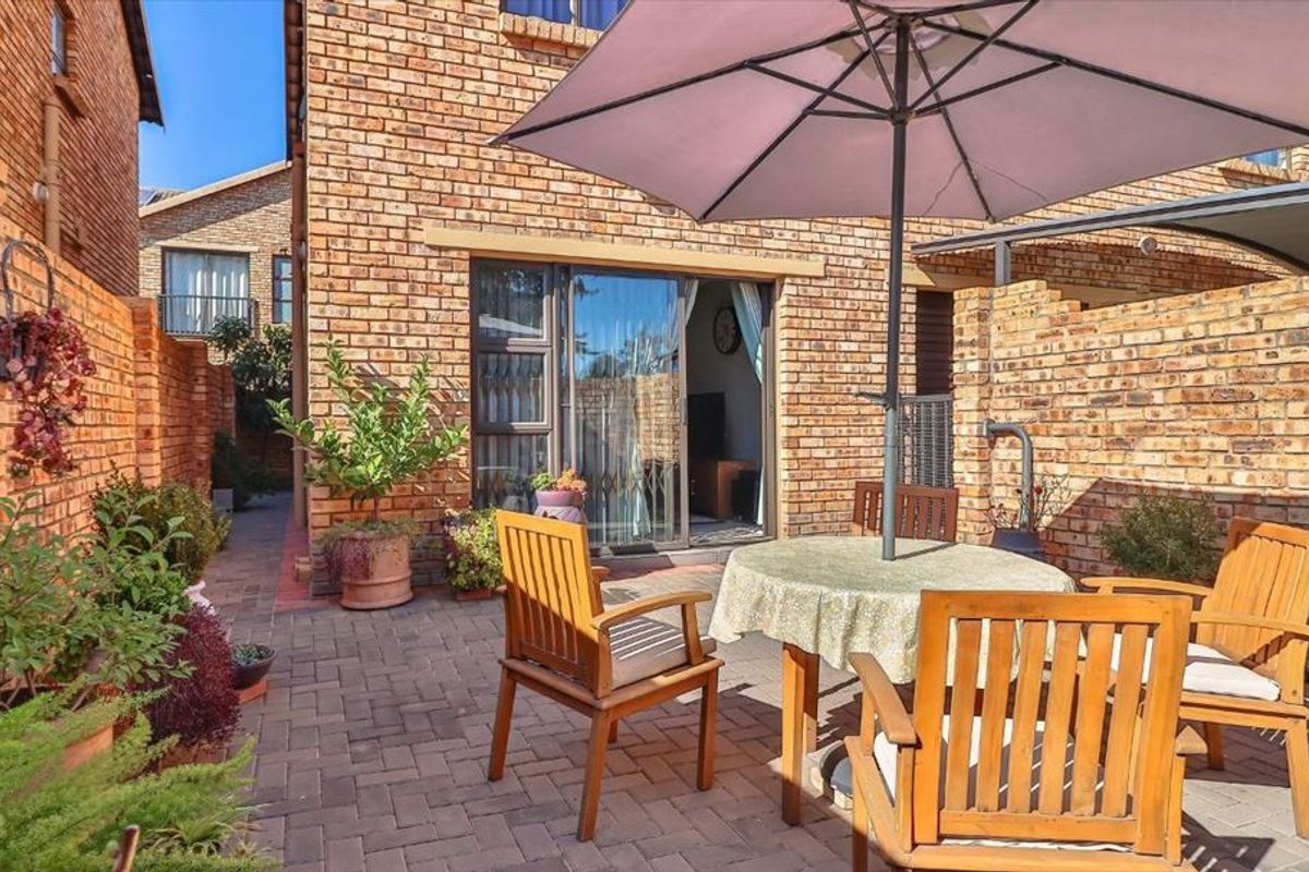 A private paved patio area featuring face brick walls and direct access to the interior through a sliding glass door.