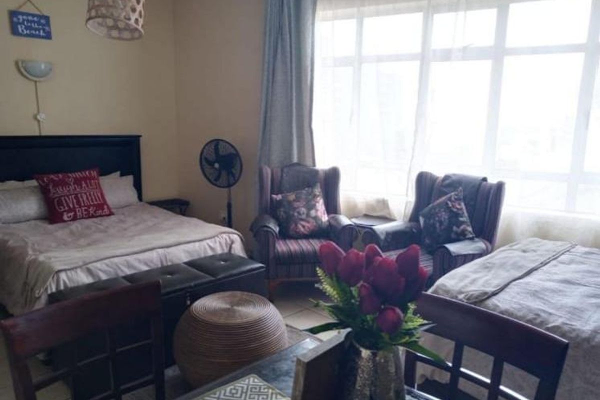 A bedroom featuring a large window that allows for natural light, providing a functional space with standard finishes.