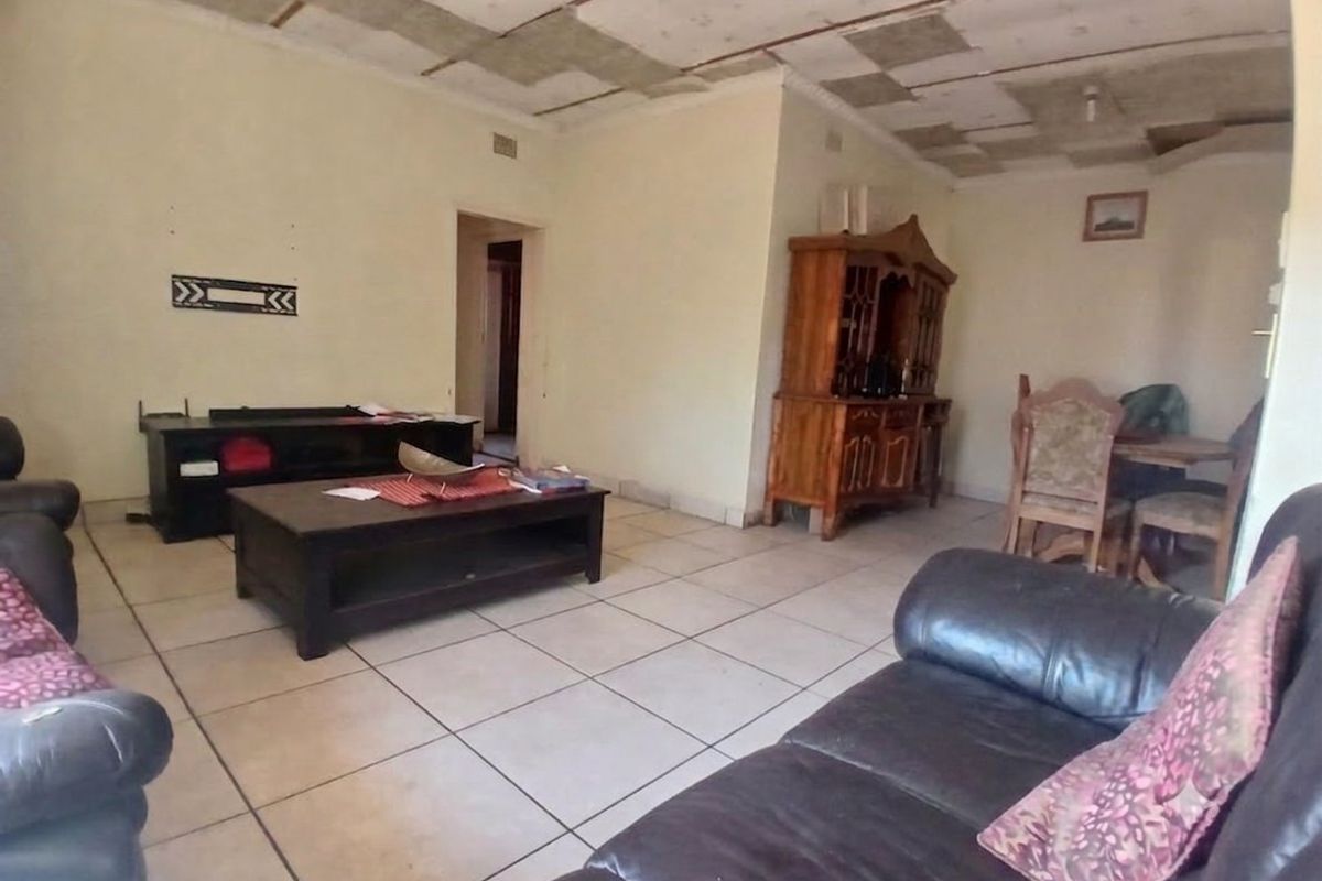 Spacious living area featuring ceramic floor tiles and a ceiling in need of repair or replacement.
