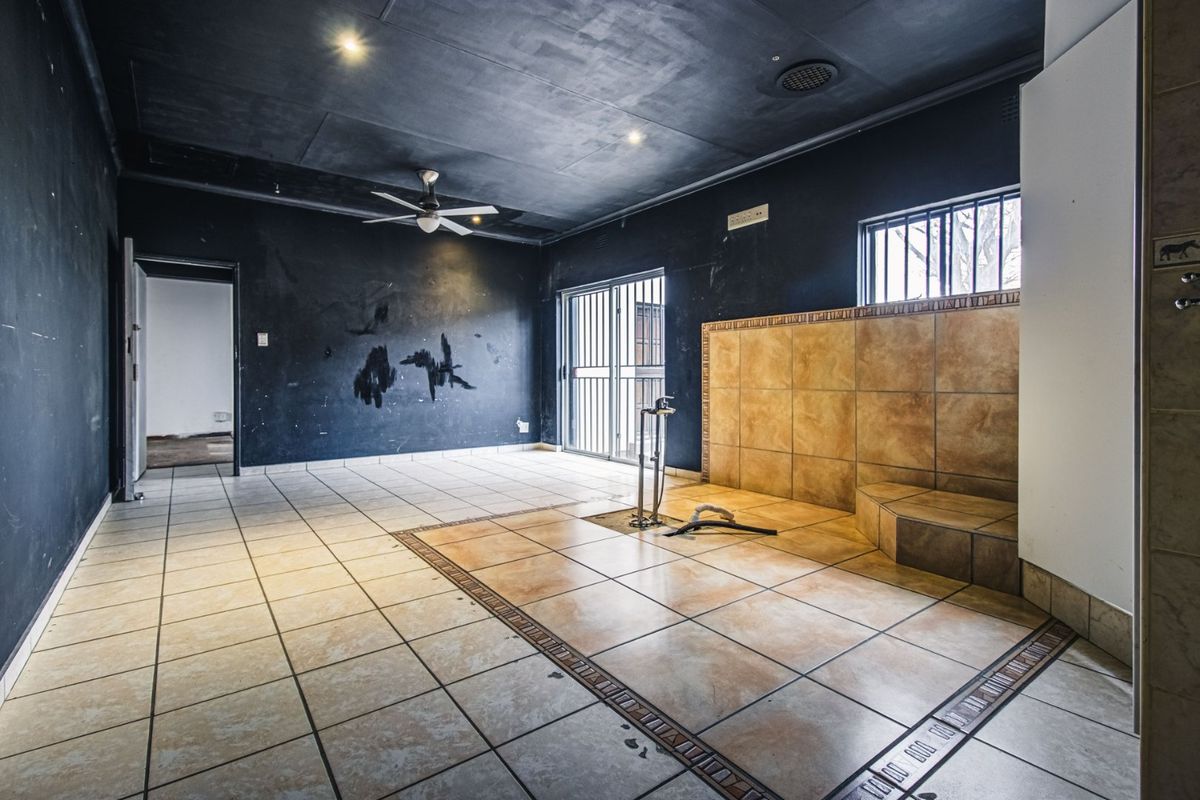 Spacious bathroom area featuring tiled flooring, a tiled feature wall, and dark painted walls. The space is currently vacant and requires cosmetic refurbishment.