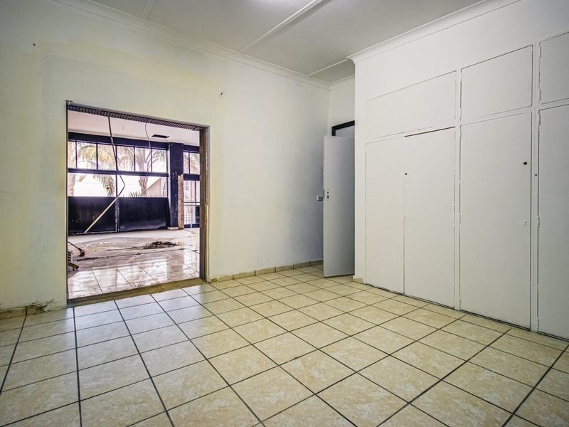An empty office space featuring ceramic tiled flooring and built-in storage cupboards, providing a blank canvas for commercial renovation.