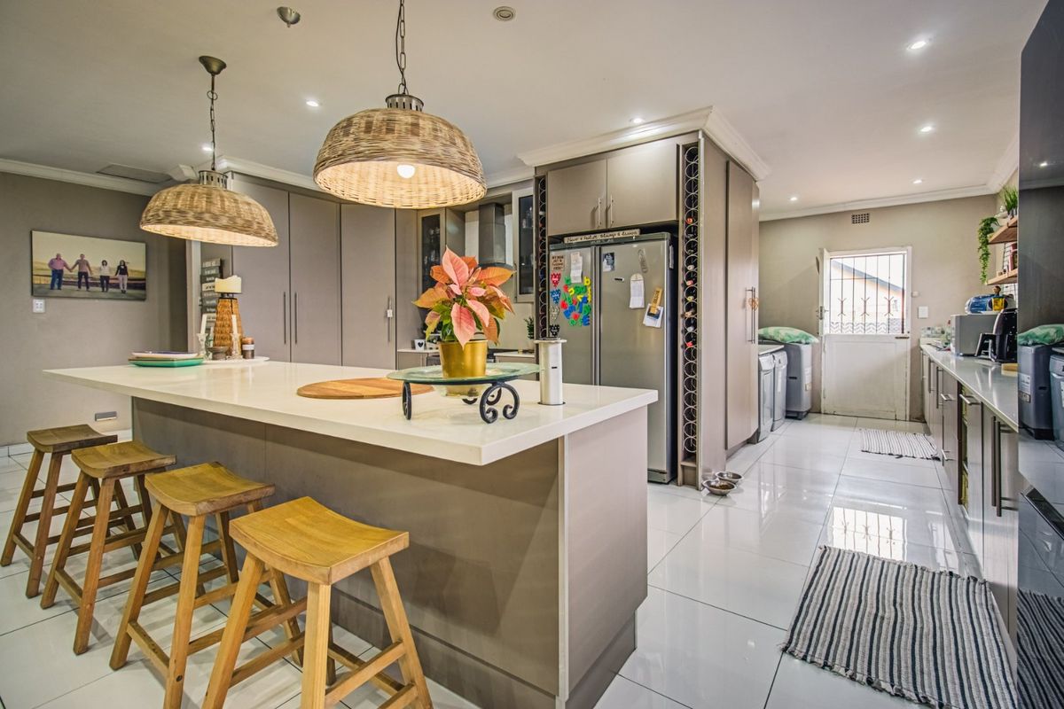 Modern kitchen featuring a large central island with stone countertops, ample built-in cabinetry, integrated wine storage, and sleek tiled flooring throughout.