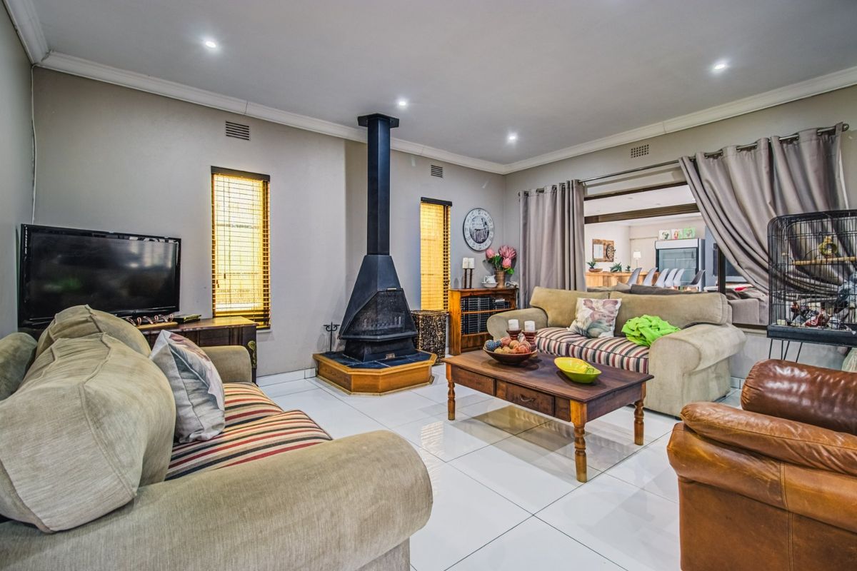 A comfortable living room featuring a prominent freestanding fireplace, polished tiled flooring, and recessed lighting, creating a warm and inviting atmosphere.