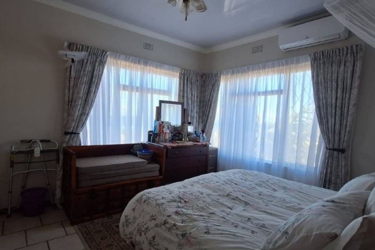 A well-lit bedroom featuring tiled flooring, a built-in wardrobe, and a wall-mounted split-system air conditioner.