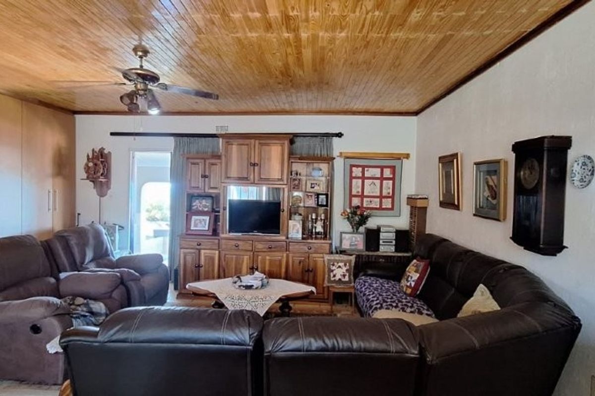 Spacious living room featuring a warm timber tongue and groove ceiling, tiled flooring, and extensive built-in cabinetry for storage.