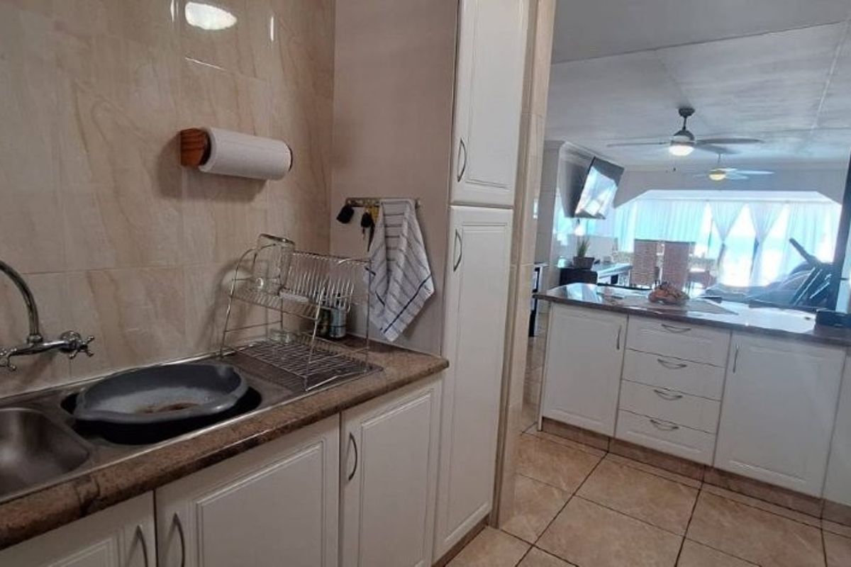 A functional kitchen featuring built-in cabinetry, granite countertops, and a double bowl sink, with an open-plan layout leading into the living area.