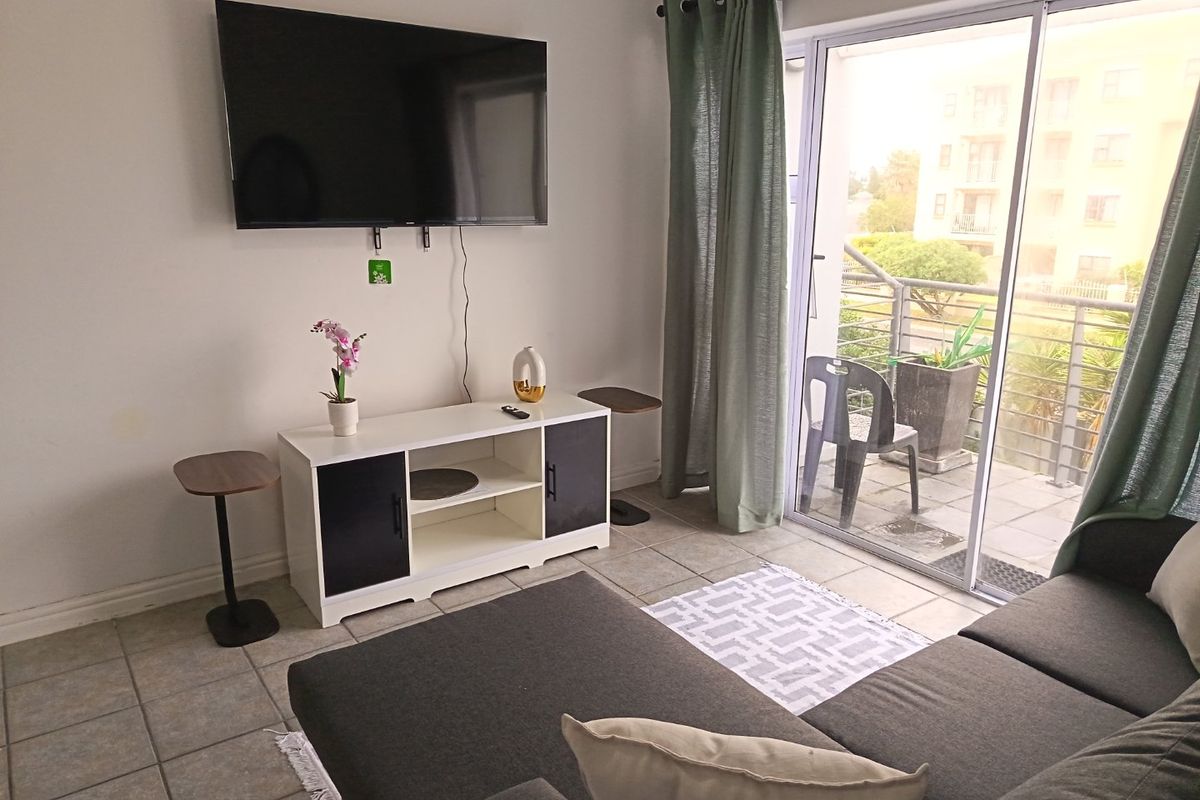 A living room featuring tiled flooring and a sliding glass door providing direct access to an outdoor balcony area.