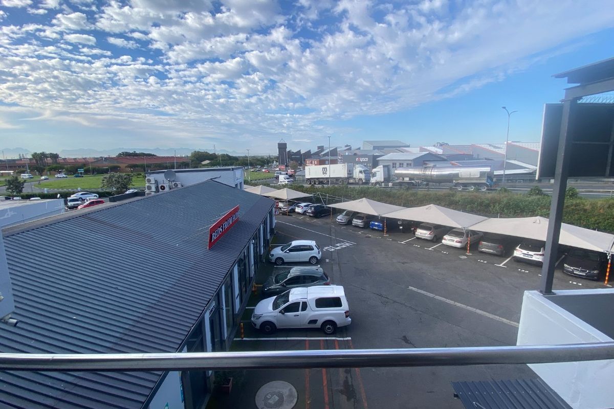 Elevated view of a commercial property featuring an asphalt parking area with shade cloth carports and surrounding industrial infrastructure.