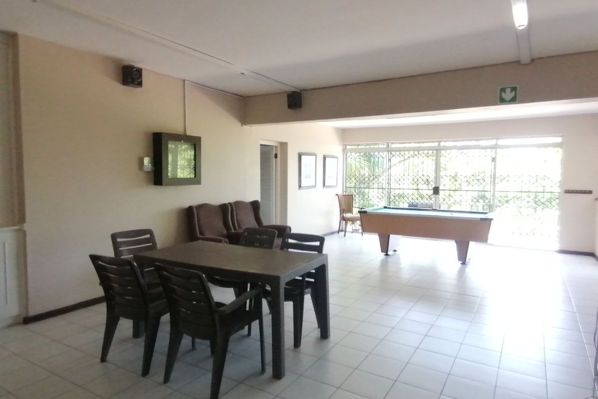 Spacious living area featuring tiled flooring and large sliding glass doors with security gates, providing ample natural light and access to the outdoors.