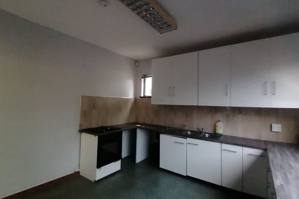 A functional, empty kitchen featuring white built-in cabinetry, laminate countertops, a built-in oven, and a stainless steel sink.