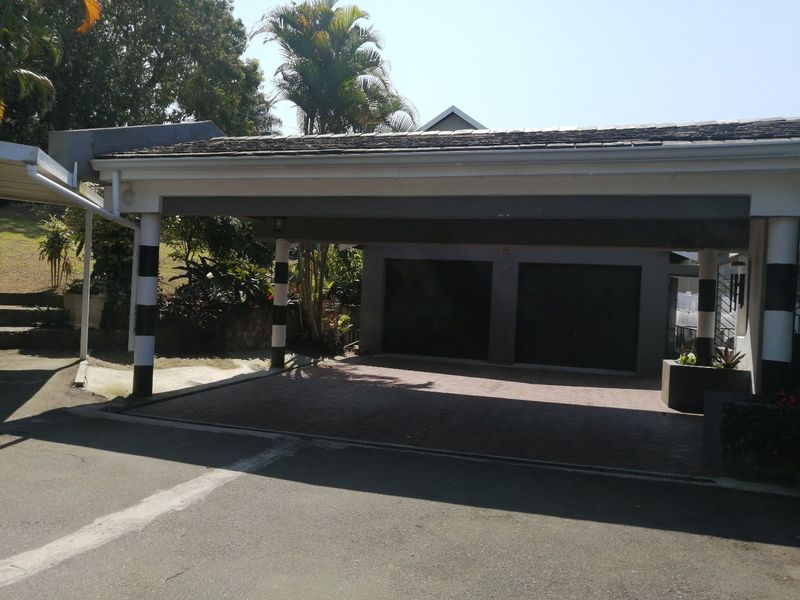 A double garage with a paved driveway and an attached covered carport area.