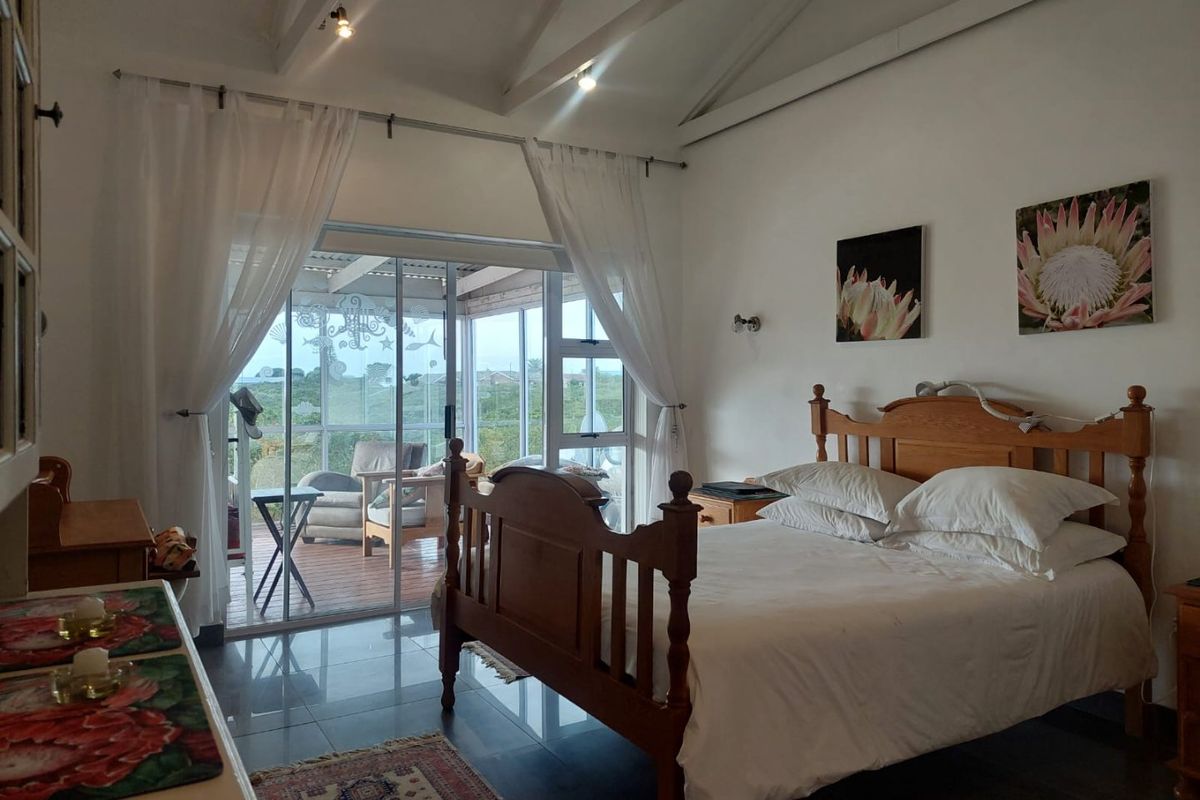 Spacious bedroom featuring vaulted ceilings with exposed beams, tiled flooring, and large sliding glass doors providing direct access to an outdoor patio area.