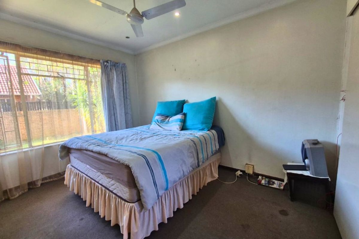 A bedroom featuring a ceiling fan, built-in cupboard, and carpeted flooring. The room requires cosmetic updates to improve its overall condition.