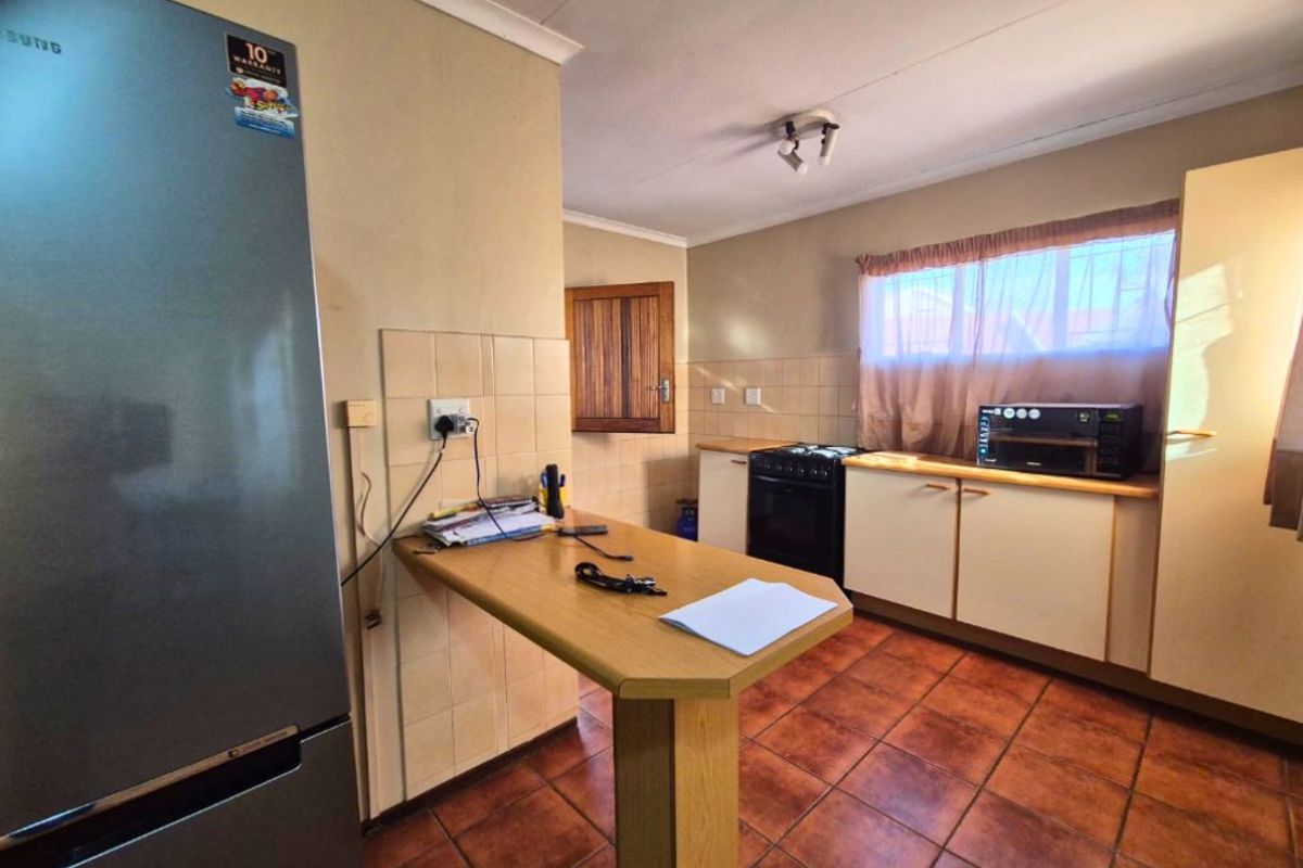 A functional kitchen featuring tiled flooring, built-in cabinetry, a tiled splashback, and a breakfast counter, offering a practical layout for daily meal preparation.